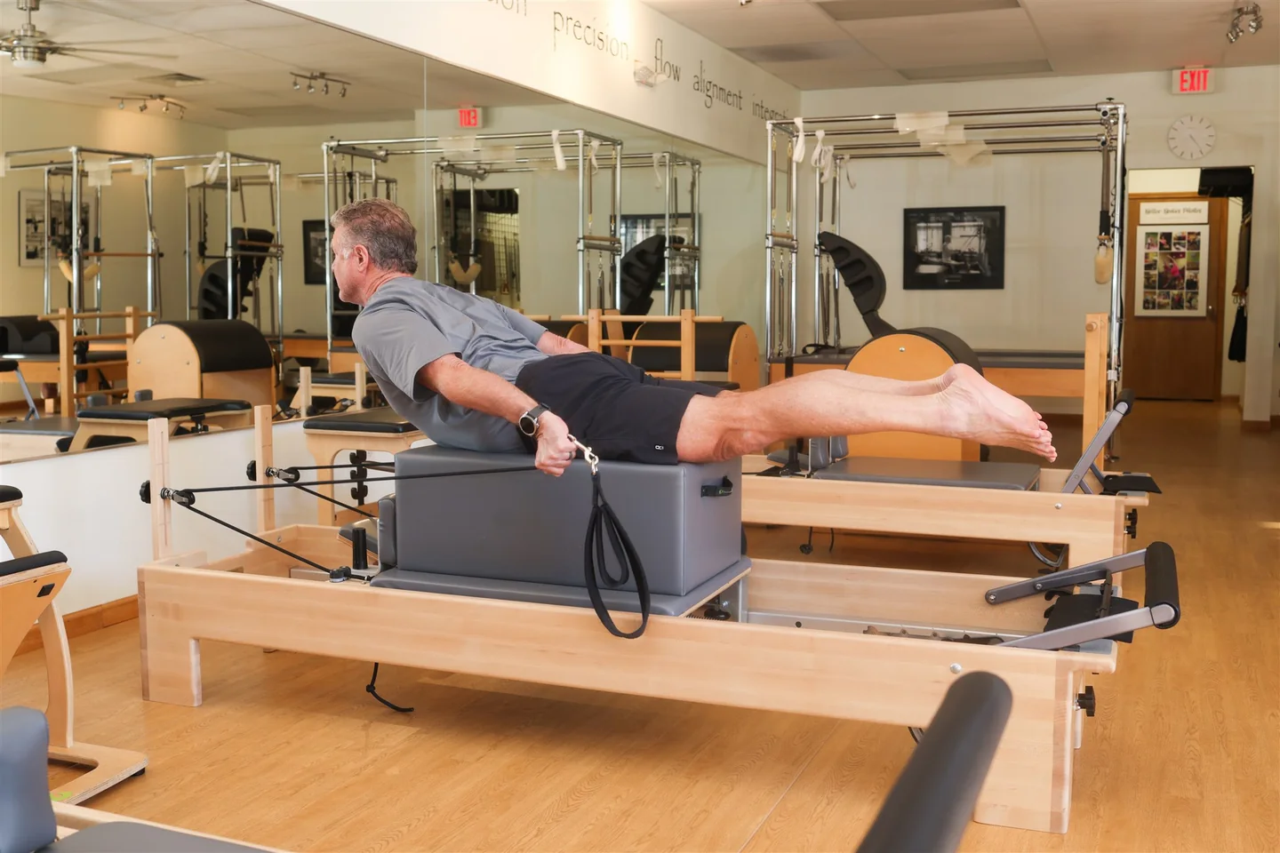 A client practices with straps while lying on a long box on a Lakewood reformer