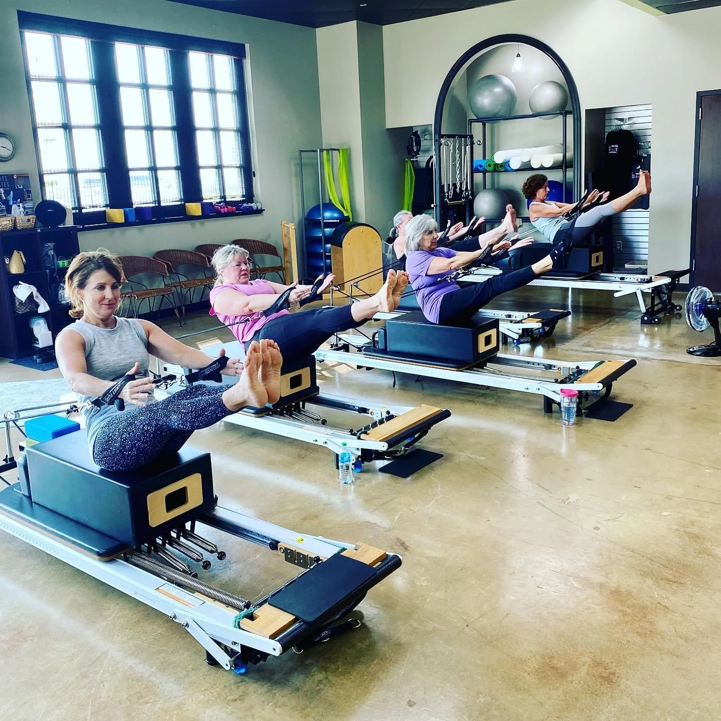 Clients sitting on reformers during a group class in the Longview studio