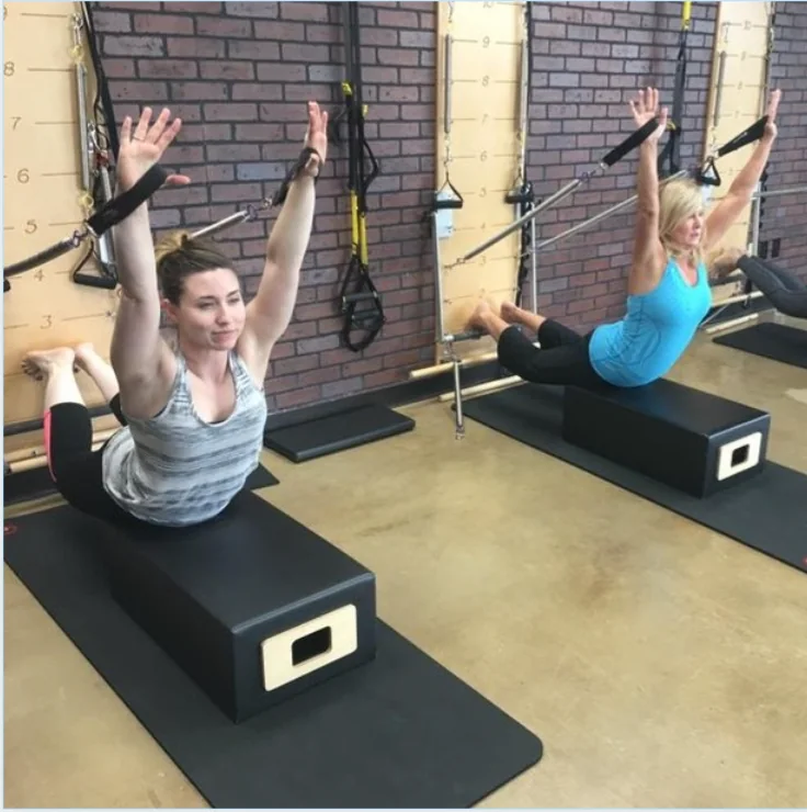 Clients reach overhead during Pilates tower work in Longview