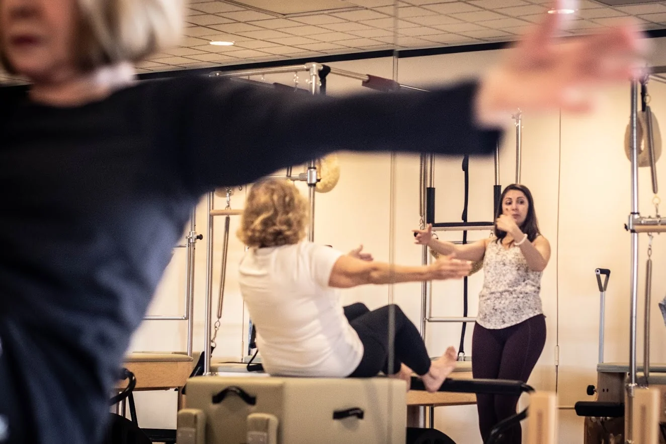 An instructor supports a client in the Overland Park studio, with equipment in the foreground