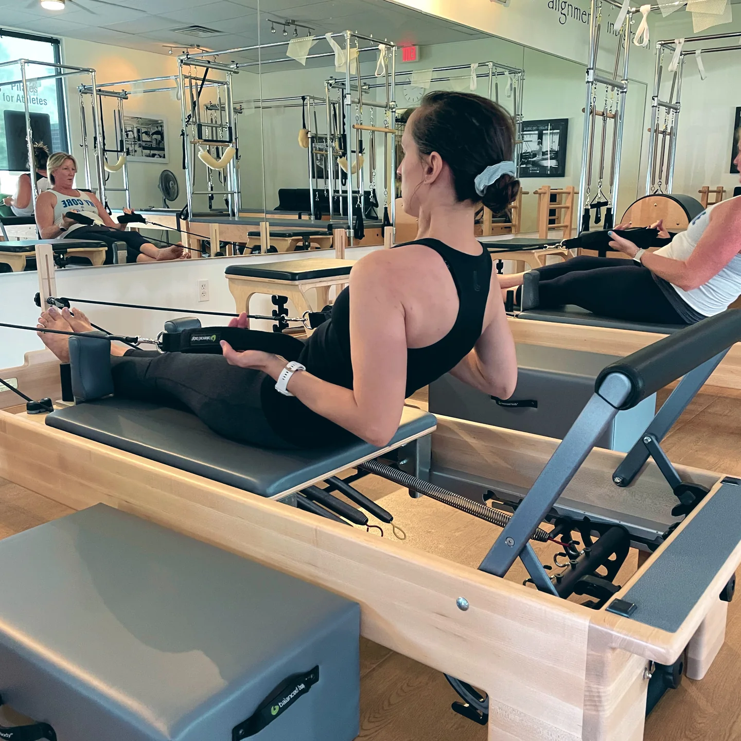 A client sits upright on a Lakewood reformer while working with resistance straps